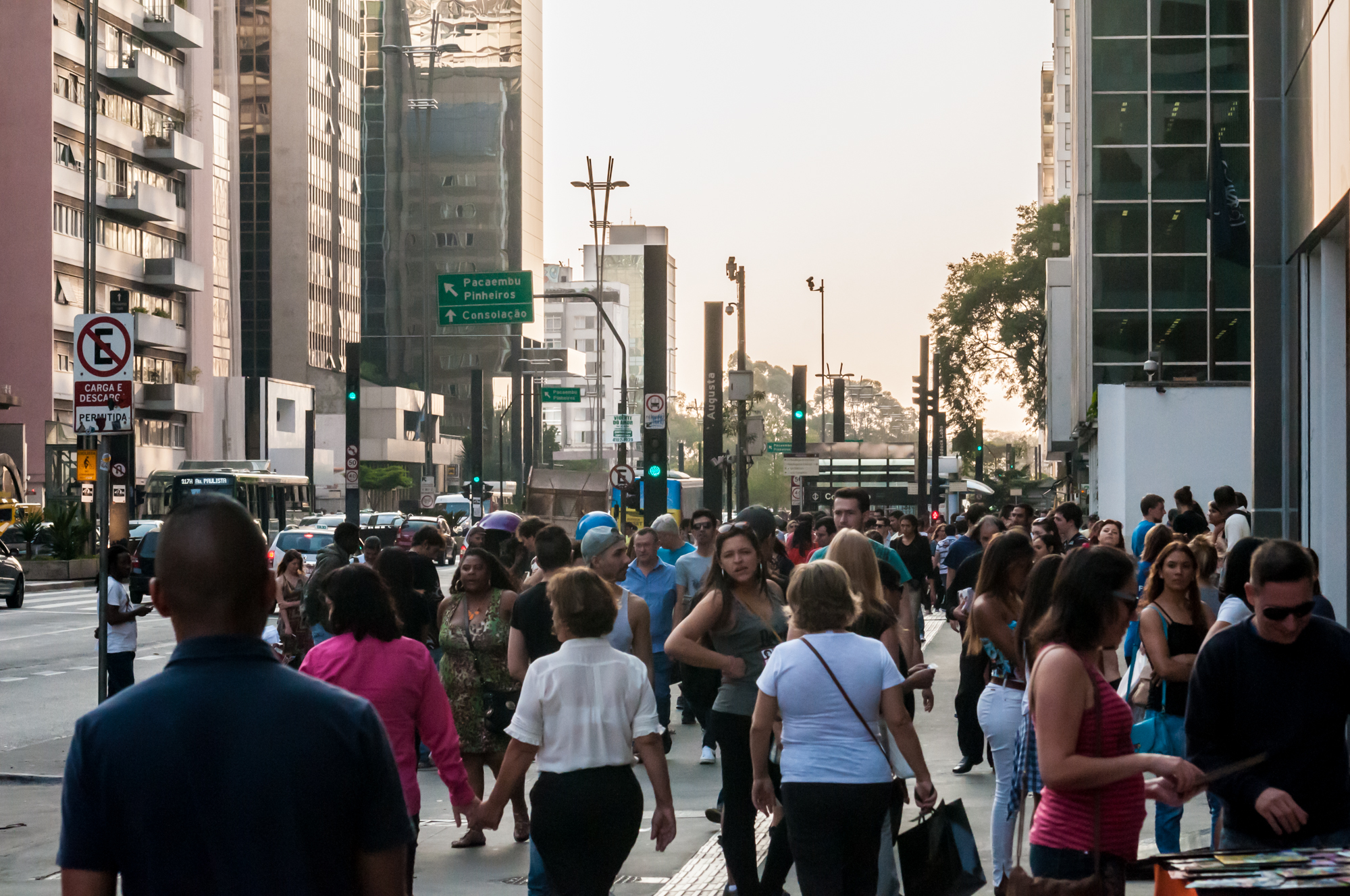 Pedestres na Avenida Paulista, entre edifícios e sinalização urbana.